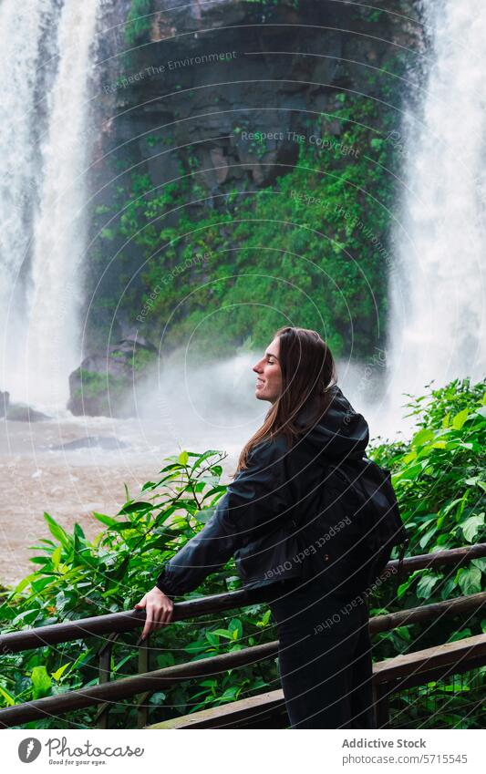 Happy female tourist enjoying the majestic Iguazu Waterfalls iguazu waterfalls woman mist greenery nature travel argentina observation adventure outdoors happy