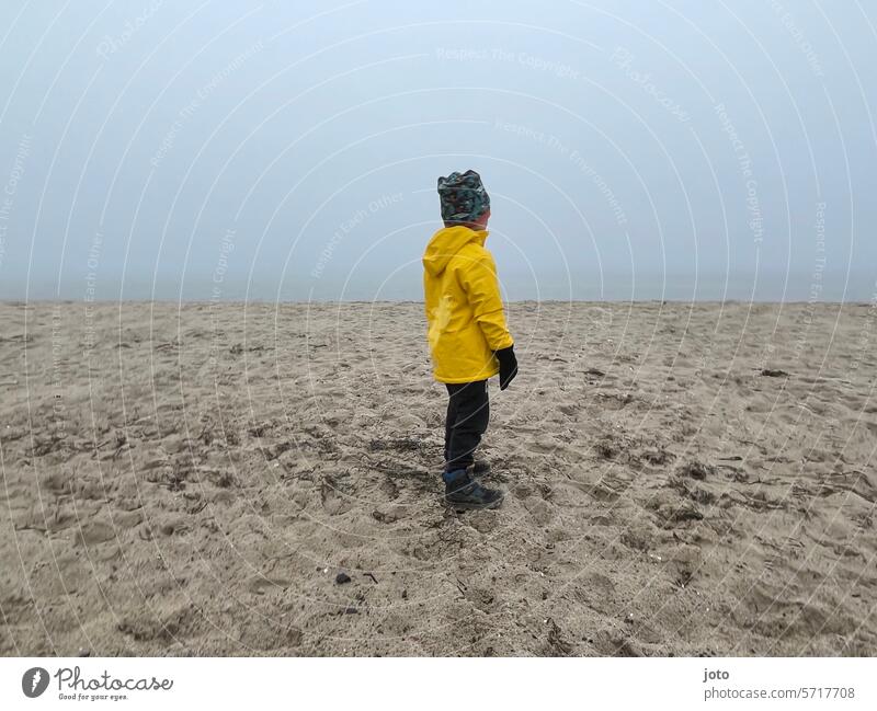 Child standing on the beach with a view of the sea on a foggy day Autumn Autumnal autumn atmosphere Dreary Exterior shot Empty Nature Water Gloomy October