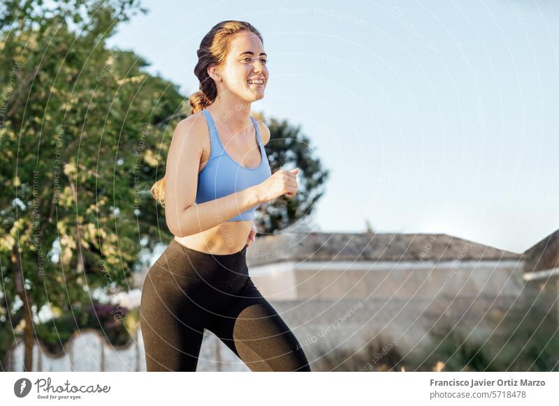 Young woman in sportswear running in the park outdoor lifestyle jogging young female fitness exercise runner athlete nature healthy adult training workout