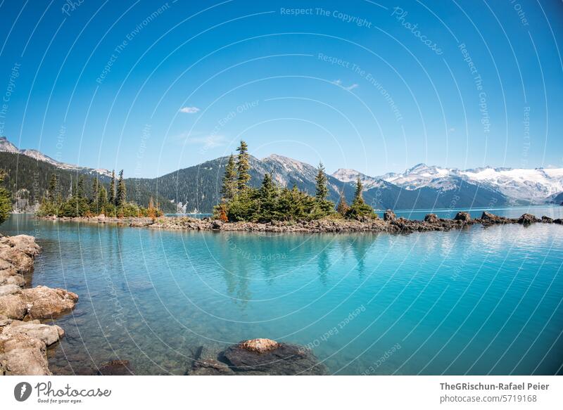 small island with trees in the lake in front of mountains Canada Forest Mountain Vantage point Hiking Tree Panorama (View) Blue sky sunny migrating vacation Sky