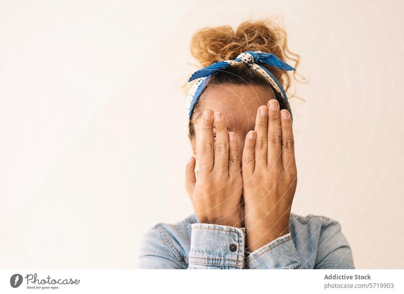 A woman conceals her face with her hands, showcasing a unique hand structure post-surgery with missing thumbs, set against a simple background cover absence