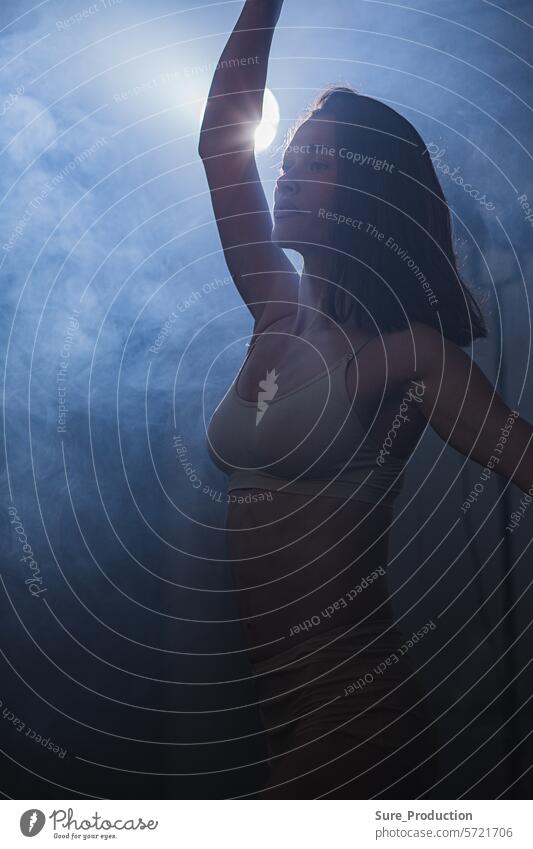 Vertical composition. Ballerina in the studio at rehearsal. Spotlights and fog in blue tones. Sexually vertical composition ballerina spotlights sexually