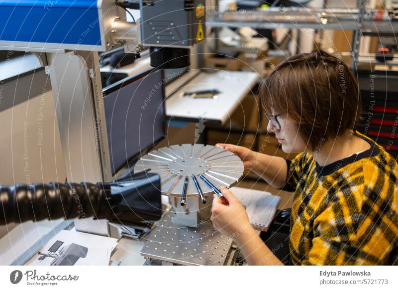 Woman operating a machine that prints logos on pens business employee factory female industrial industry job logistics manufacture manufacturing occupation