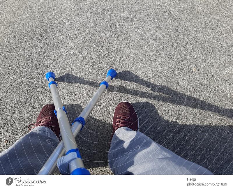 rest Break Human being Legs props crutches Illness Stroll pause Pants Footwear Light Shadow off Brown Blue Gray wine-red Feet Colour photo Exterior shot Jeans