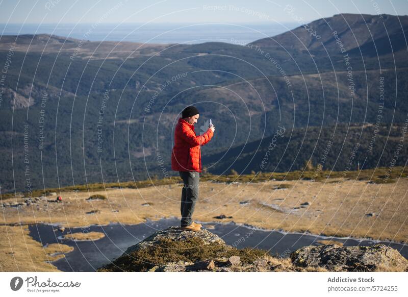 Adventurer taking photos on mountain summit adventurer photography red jacket smartphone nature landscape outdoors travel rocky peak person vista scenery hiking