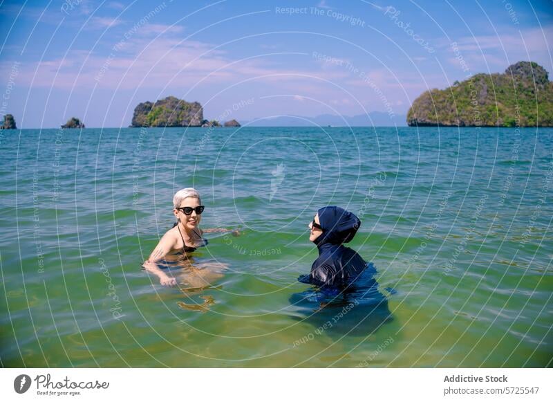 Two women of diverse cultures enjoying the sea together burkini bikini swim cultural diversity friendship water beach island scenic modesty muslim attire