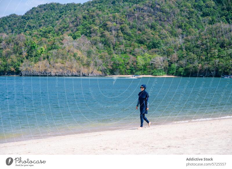 Muslim woman enjoying beach walk in burkini modest swimwear muslim walking shoreline nature tranquil water sand suit modesty female outdoor summer tropical