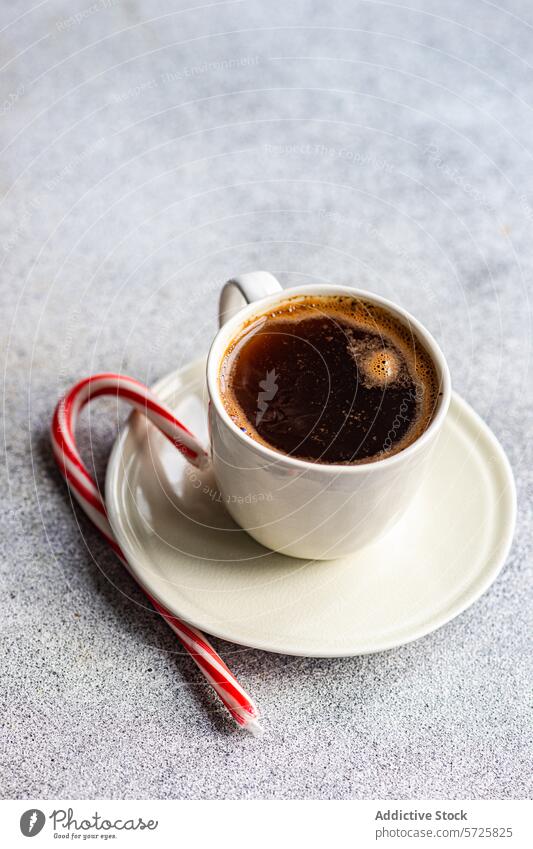 Freshly brewed coffee in a mug with a candy cane morning hot drink beverage caffeine white red breakfast cozy fresh saucer silverware spoon tabletop kitchenware