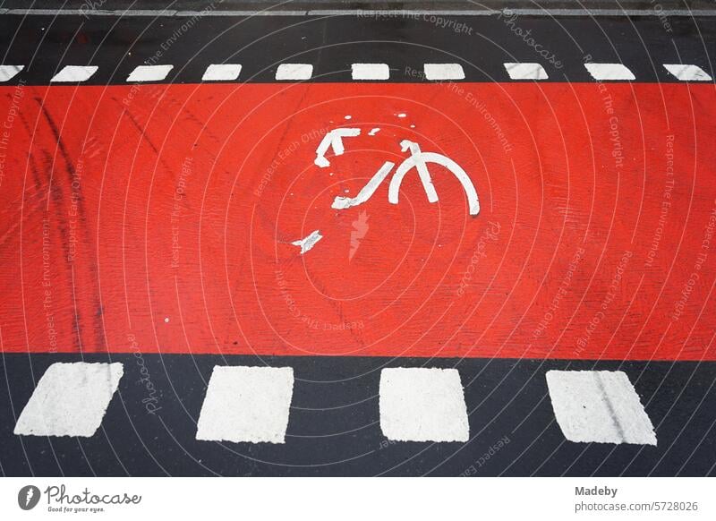 Old road markings in red and white on gray asphalt of the cycle path on Hanauer Landstraße in the Ostend district of Frankfurt am Main in Hesse accident cover