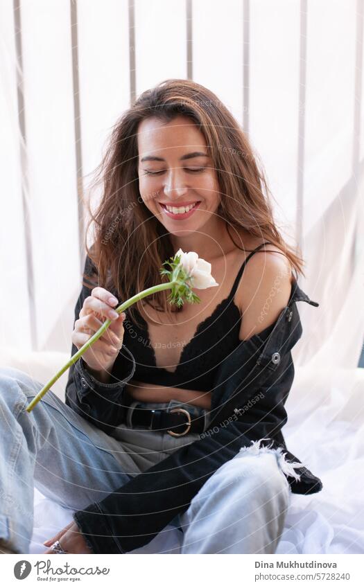 beautiful woman smiling in grunge outfit with white flower sitting on the balcony of apartment 25 to 30 years Young woman Grunge grunge look Clothing outfits