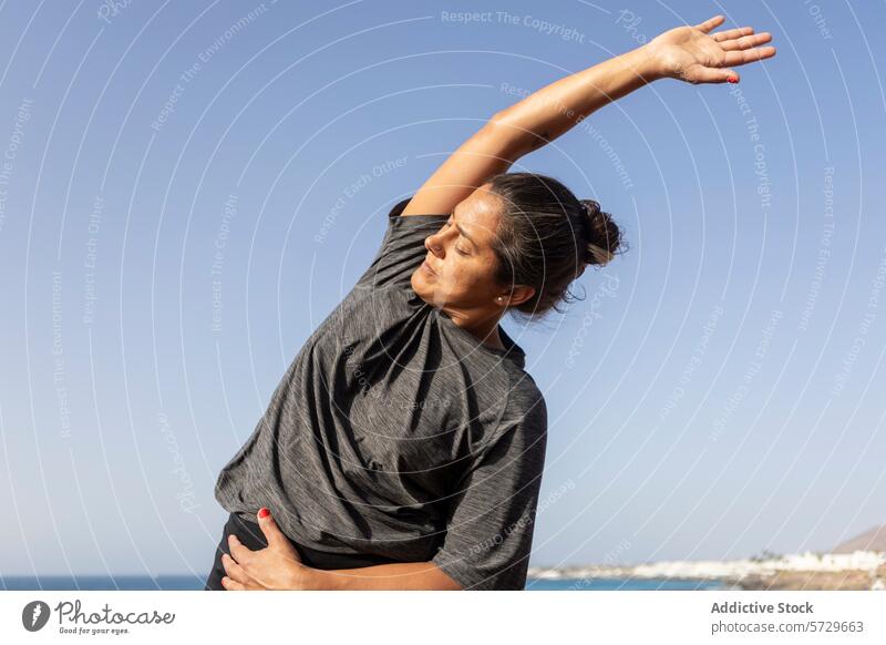 Woman stretching at beach side outdoor gym fitness woman exercise sea health active lifestyle side stretch wellness workout daytime sky leisure female physical