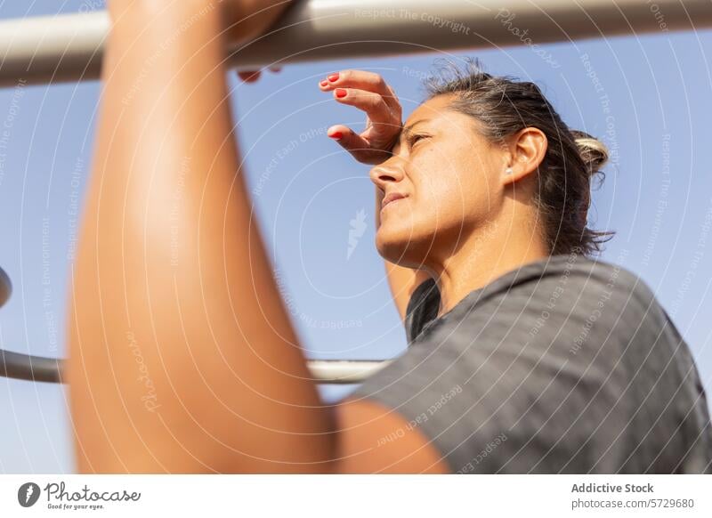 Determined woman exercising at outdoor beach gym exercise fitness health active lifestyle sport workout clear sky sea determined focused using equipment