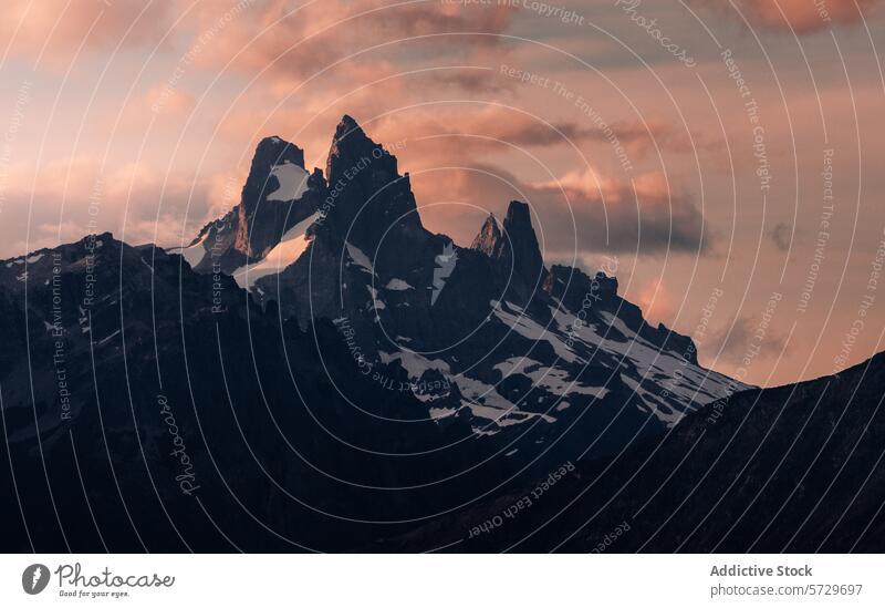 The fading light of twilight casts a warm glow over the iconic, jagged spires of the Patagonian mountains, highlighting their snow-capped majesty Argentina