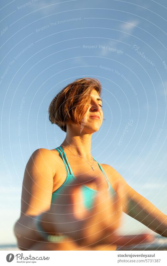 A woman performs meditation exercises on the beach, after a Pilates session at sunset yoga mediterranean spain female person lifestyle healthy young training