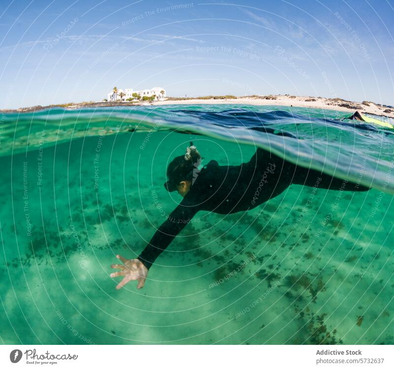 An idyllic scene featuring a snorkeler in a sleek wetsuit, exploring the underwater world near a coastal villa, with a clear view of the shore above exploration