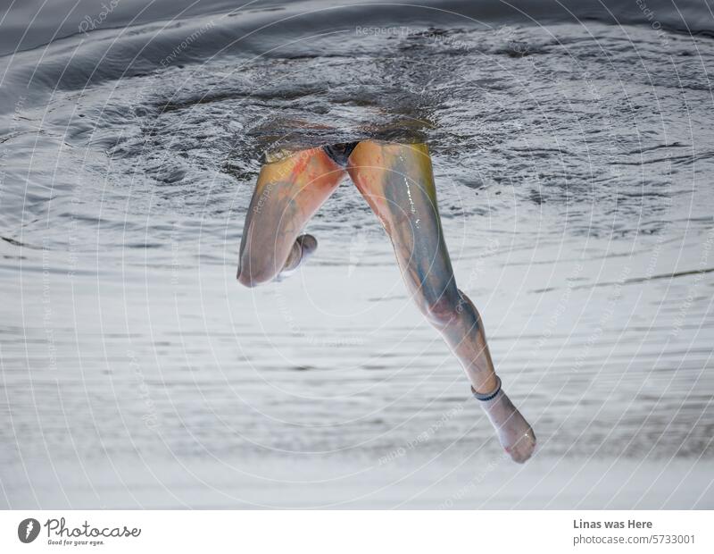 The world becomes more fascinating when viewed upside down, much like this rotated image featuring a colorful girl with long legs. With wet socks and a joyful expression, she revels in the refreshing waters of the lake, showcasing nature's beauty.