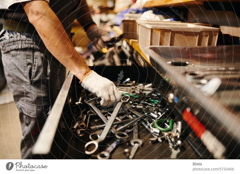 Cropped image of mechanic taking wrench from drawer tool choose mess hands glove repair vehicle bike garage blue collar fixing broken motorcycle assemble job