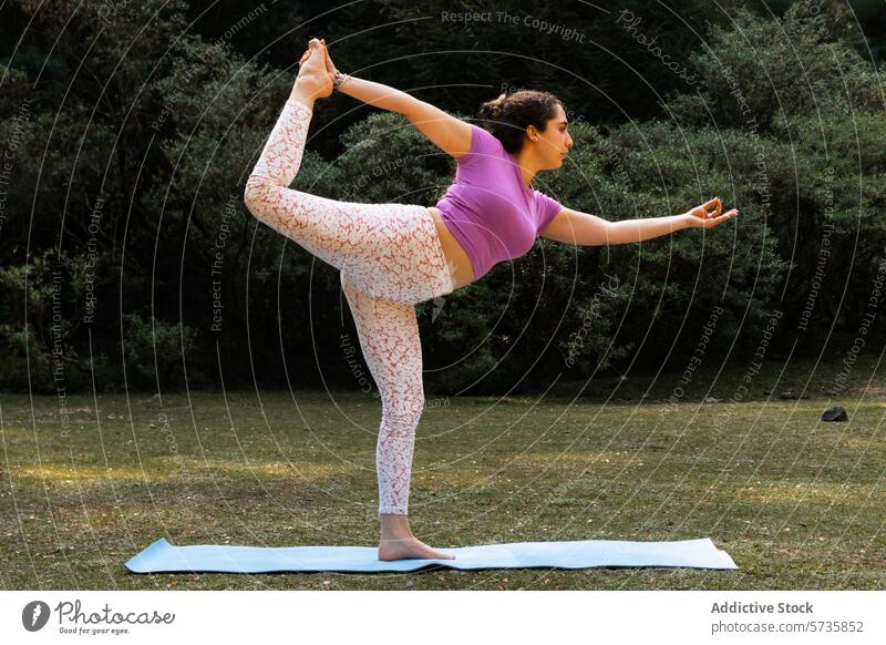 A yogini demonstrates Natarajasana, the Lord of the Dance Pose, with precision and grace against a backdrop of natural foliage yoga dancer pose outdoor nature