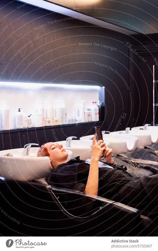 Relaxing at a Hair Salon with Modern Amenities hair salon woman relaxing smartphone hair treatment chair interior modern awaiting hair care beauty