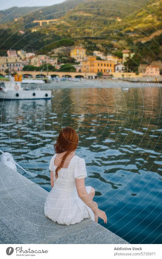 Serene moment by the sea with a woman in white white dress coastal town boat hill sitting scenic overlook serenity tranquility peaceful waterfront harbor