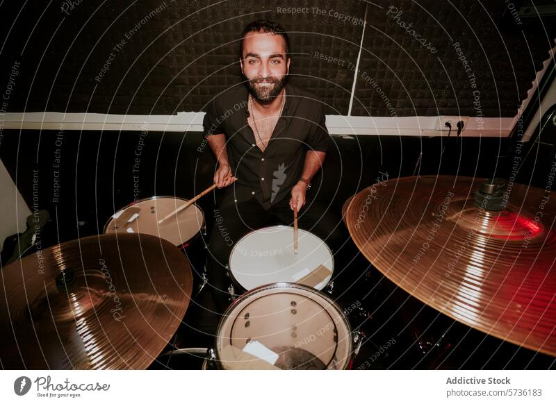 Male drummer playing in a music band setup male man stick cymbal smile looking at camera instrument performance musician sit black shirt casual entertainment