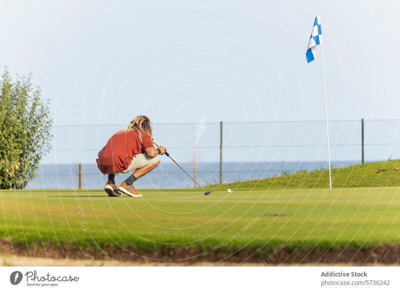 Unique golfer with dreadlocks preparing to putt blonde course sunny crouch align golf club ball green flag sport outdoor concentration hobby leisure unique