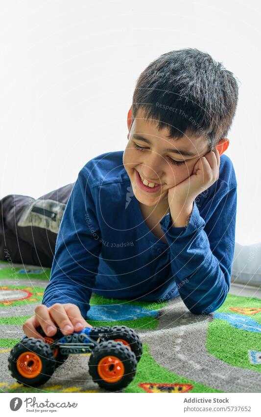 Boy Smiling While Playing With Toy Car on Floor child boy play toy car play mat smiling looking away floor indoor happy joy leisure activity playtime casual