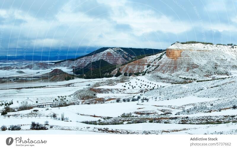 Striking layers of snow, red rock, and vegetation paint the highlands of Central Guadalajara, contrasted by a dramatic winter sky landscape outdoor nature cold