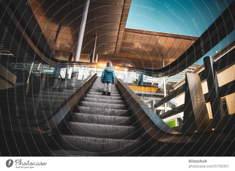 Little girl alone on an escalator Escalator Architecture Transport Train station Station Town Promotion urban Upward Stairs Modern Girl Child City travel people