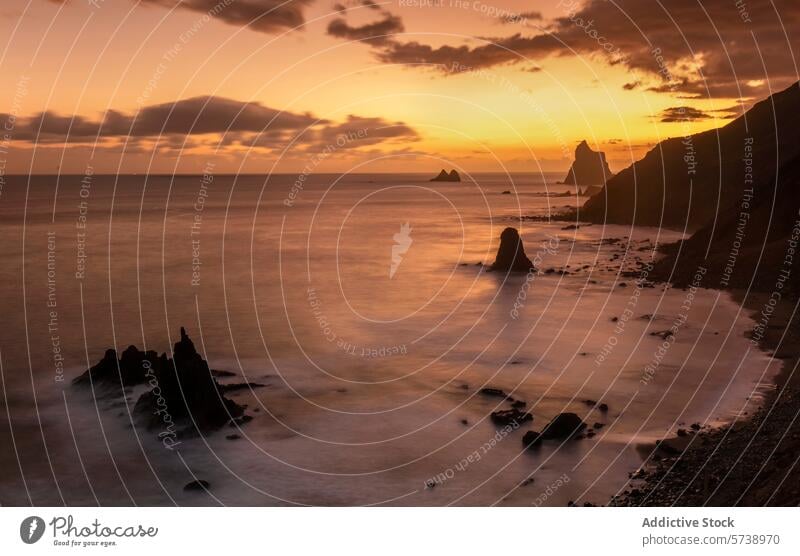 The last light of day illuminates Playa de Benijo with a soft amber glow, highlighting the unique rock formations and tranquil sea beach dusk sunset coastline