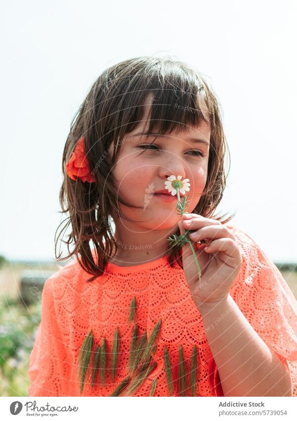 A thoughtful young girl in an orange dress examines a daisy closely, captured in a serene moment at a farm school in summer contemplation flower child nature