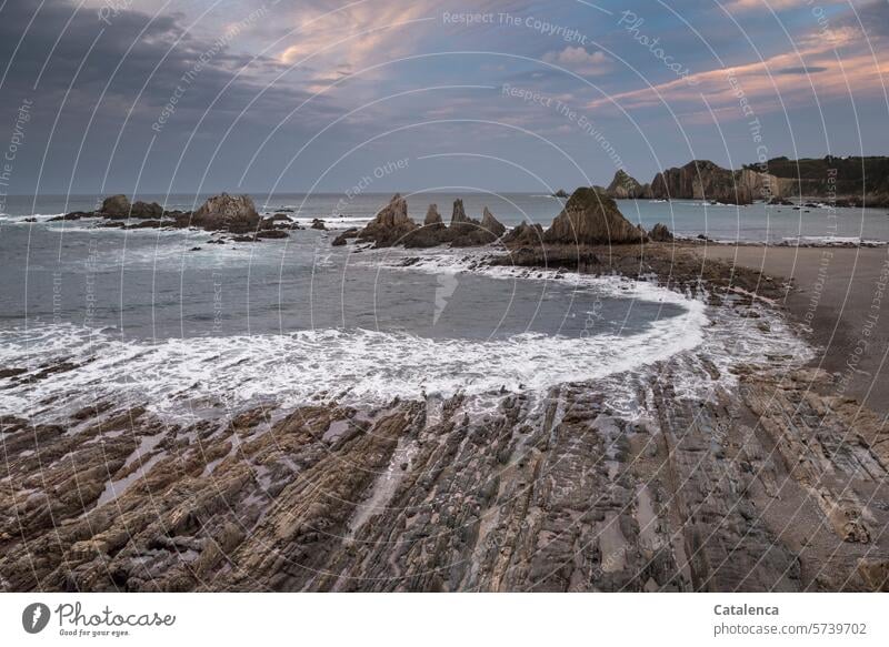 Rocky beach landscape Gray Blue Day Wet Elements coast Water Clouds Low tide High tide Surf Waves White crest rock formation stones Landscape Beach