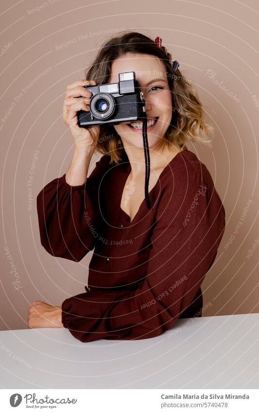 Young woman looking through a vintage camera. Photo in studio with isolated background. adult beautiful beauty blonde caucasian concept creativity expression