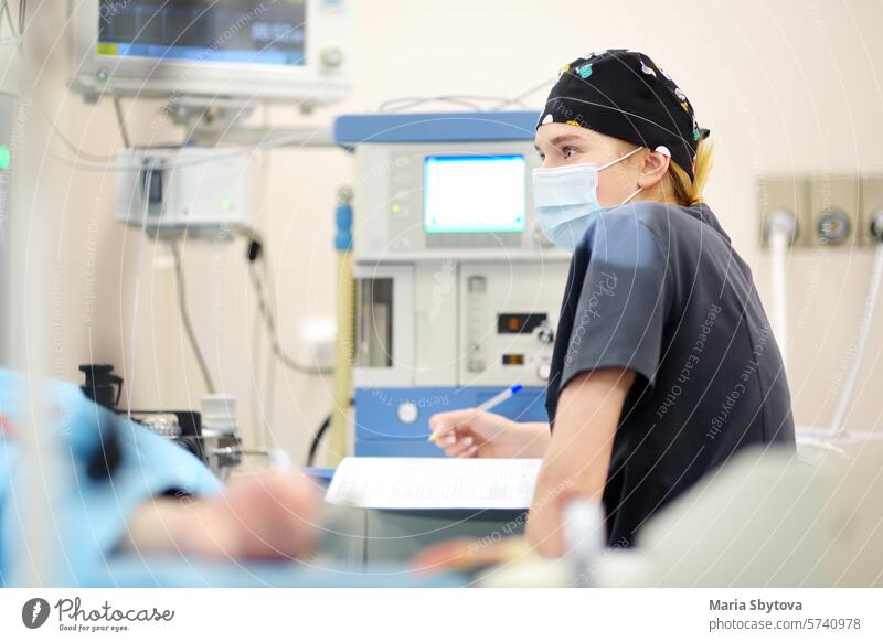 Intern surgeon records the progress of the operating room in a journal. Wearing an operating gown the anesthesiologist describes the operation in a chart.