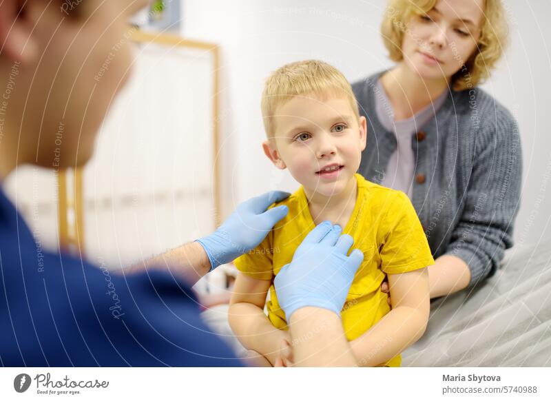 A cute toddler boy with his mother are at an appointment with a pediatrician. The doctor ENT is examines lymph nodes of a little patient. child kid test