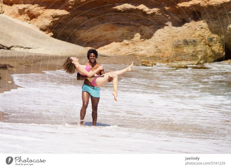 Happy diverse couple having fun on beach smile walk vacation holiday together cheerful happy joy summer sea coast relax sand ocean travel positive optimist