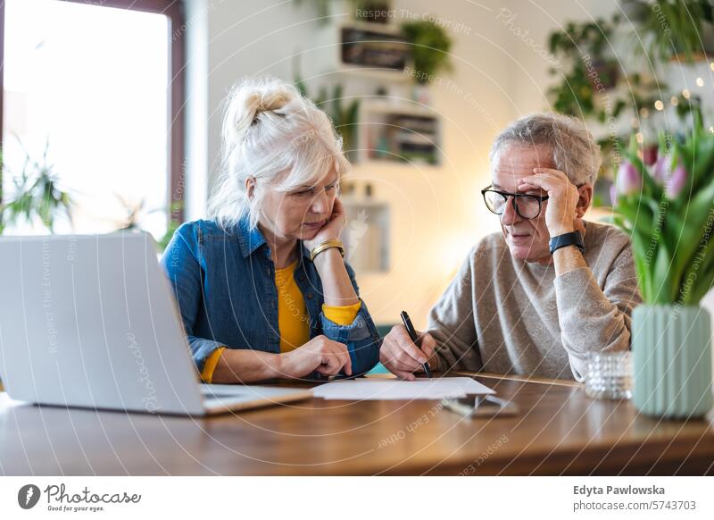 Senior couple sitting at the table discussing home finances people caucasian grey hair casual day portrait indoors real people white people adult mature retired