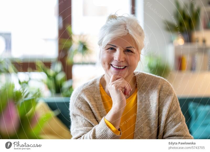 Mature woman looking at camera and smiling in her living room at home people casual day portrait indoors real people white people adult mature retired old