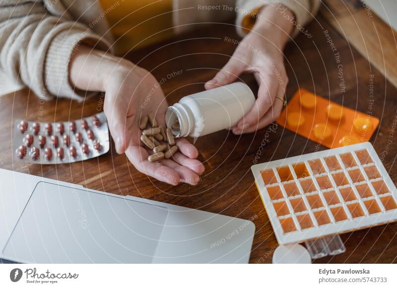 Senior woman taking pills from a bottle while sitting at the table at home people casual day portrait indoors real people white people adult mature retired old