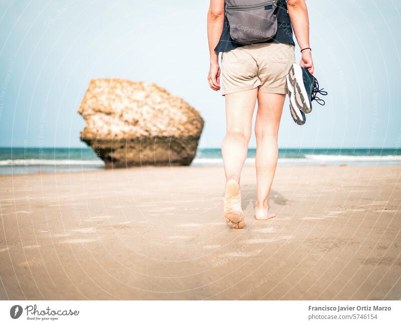 Woman walking on the beach with shoes in hand person woman sea summer vacation water sand outdoor ocean nature lifestyle girl travel female beautiful leg adult