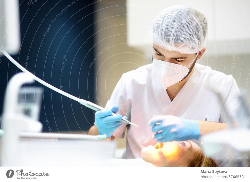 Dentist and patient at modern medical center. Doctor treats a young woman teeth in hospital. Practitioner examines the patient before orthodontists or prosthetics treatment.