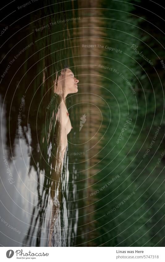 A gorgeous naked girl is floating peacefully in this dark lake’s water. An erotic image starring a beautiful nude woman in the wilderness. She drifts, lost in her thoughts.