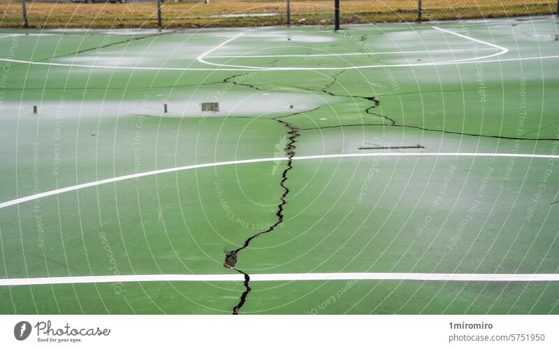 Empty outdoor green basketball court with visible cracks and white lines american asphalt competition court lines cracked surface damaged day deserted empty