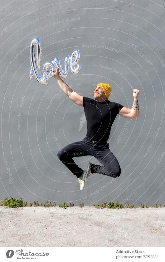 Joyful man jumping with a love balloon joy casual wear beaming shiny affection emotion happiness celebration cheerful energetic excitement fun joyful leap