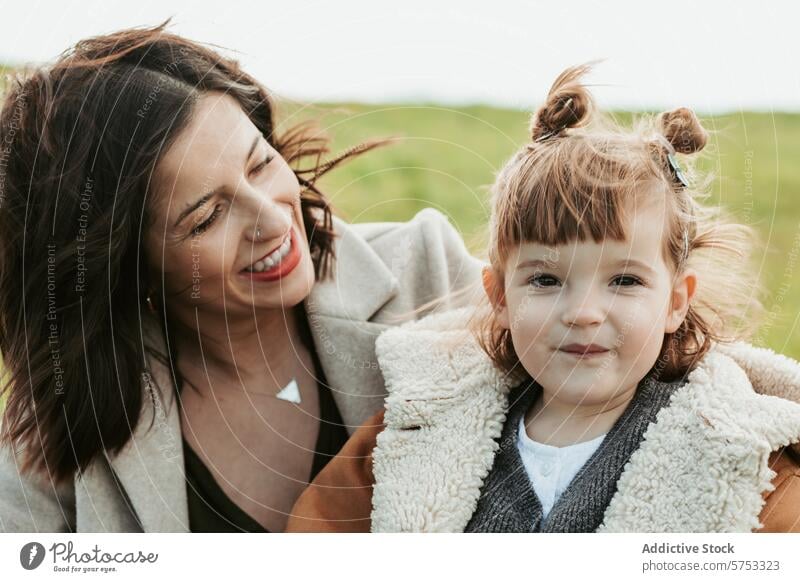 Joyful mother and daughter enjoying a day outdoors family love happiness field embrace smile genuine woman child bonding parent kid affection cheerful together