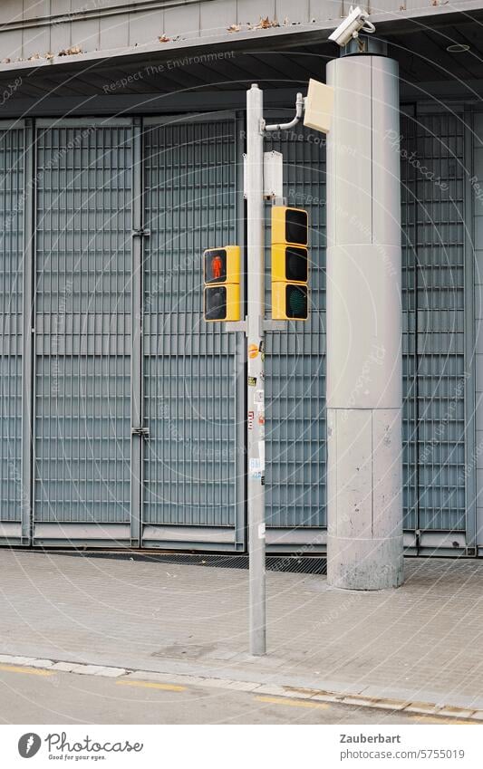 Traffic light stands in front of a gray gate, concrete column, modern and sparse Fitting Pedestrian traffic light Goal Column Concrete Gray Gloomy Sparse policy