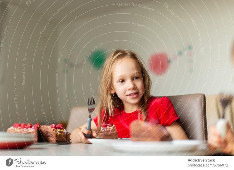 Girl enjoying a slice of birthday cake at a party girl celebration eating dessert child young happy smile red shirt sitting table festive occasion delicious