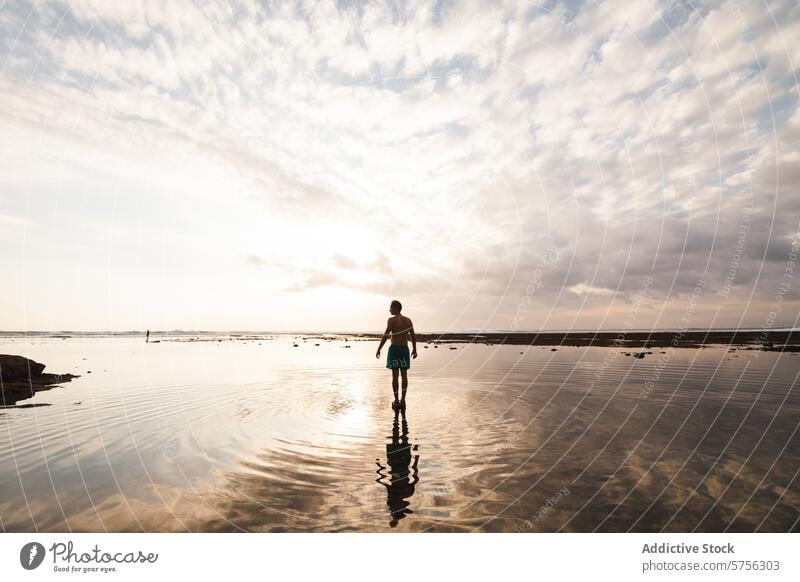 Tranquil sunset walk on Indonesian beach indonesia traveler serene silhouette reflection water sky clouds tranquil shore tourism destination holiday vacation