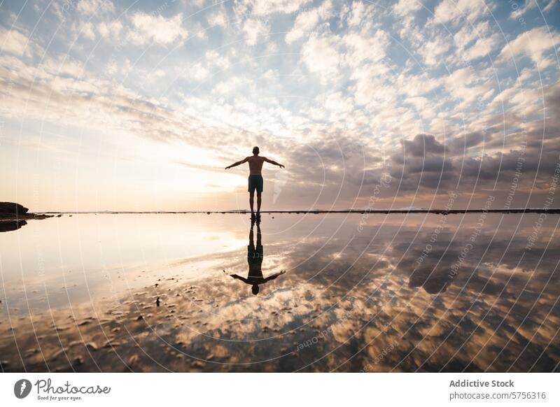 Serene beach sunset silhouette in Indonesia reflection person arms cloudy sky indonesia tranquil serene dusk travel tourism landscape nature water clouds