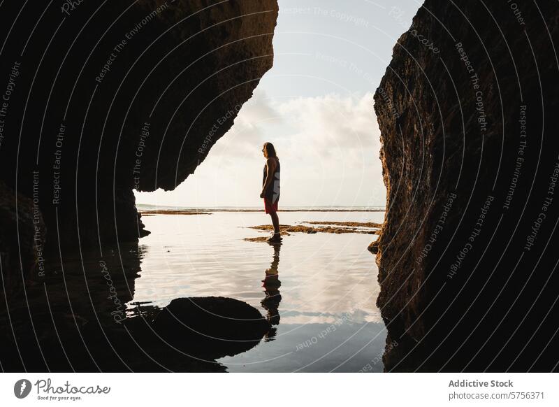 Silhouetted woman standing between sea cliffs at sunset silhouette indonesia travel reflection sky tranquil spirit journey adventure peaceful serene nature